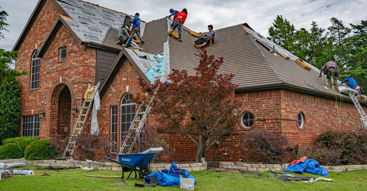 Des couvreurs travaillent sur une maison en brique à Allen, Texas, s'attaquant aux bardeaux et aux matériaux de toiture.