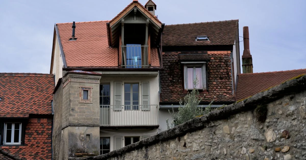 Une maison suisse pittoresque avec des toits en tuiles rouges traditionnels et un travail de pierre rustique.