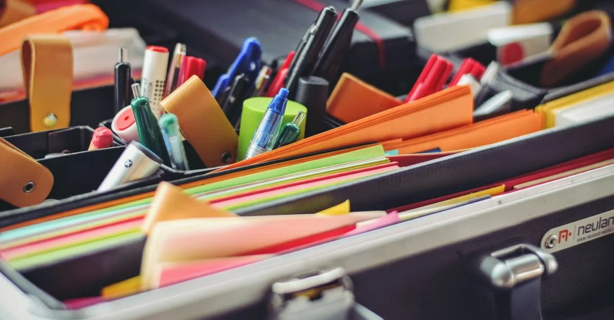 Une collection de fournitures de bureau colorées soigneusement disposées dans une mallette, parfaite pour les professionnels en déplacement.