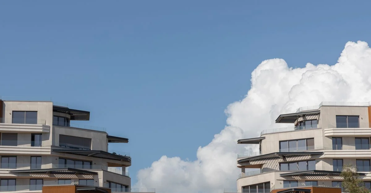 Architecture urbaine contemporaine sous un ciel bleu clair avec des nuages.