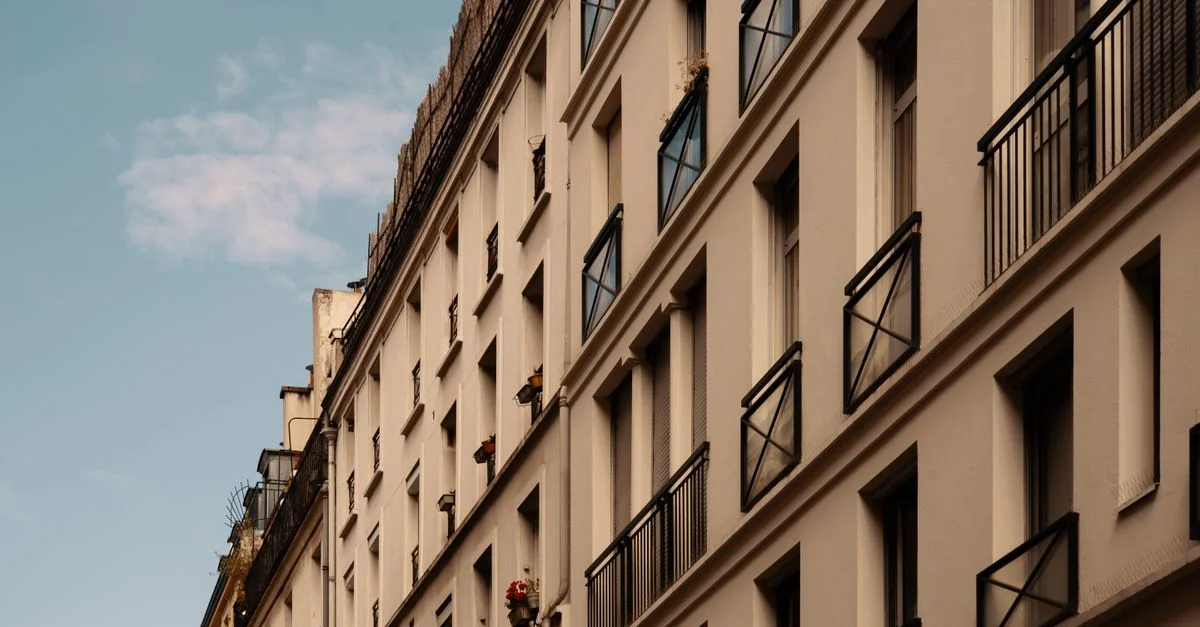 Une belle perspective de rue d'un élégant immeuble urbain à plusieurs étages avec des balcons en fer contre un ciel bleu.