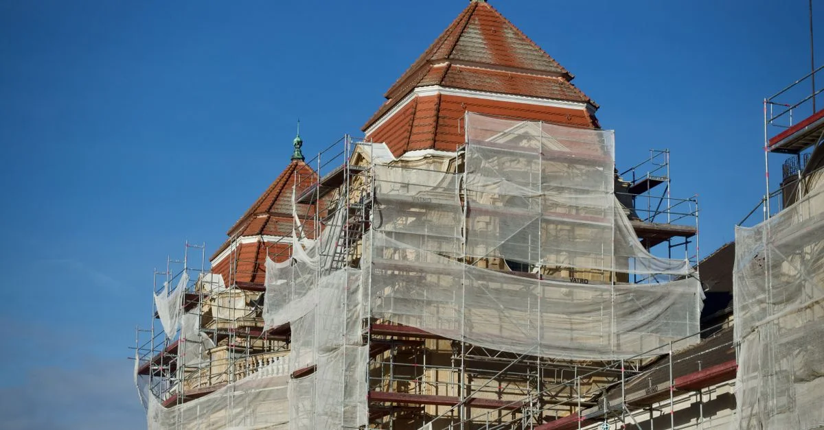 Un bâtiment historique en cours de restauration, recouvert d'échafaudages et de filets de protection.