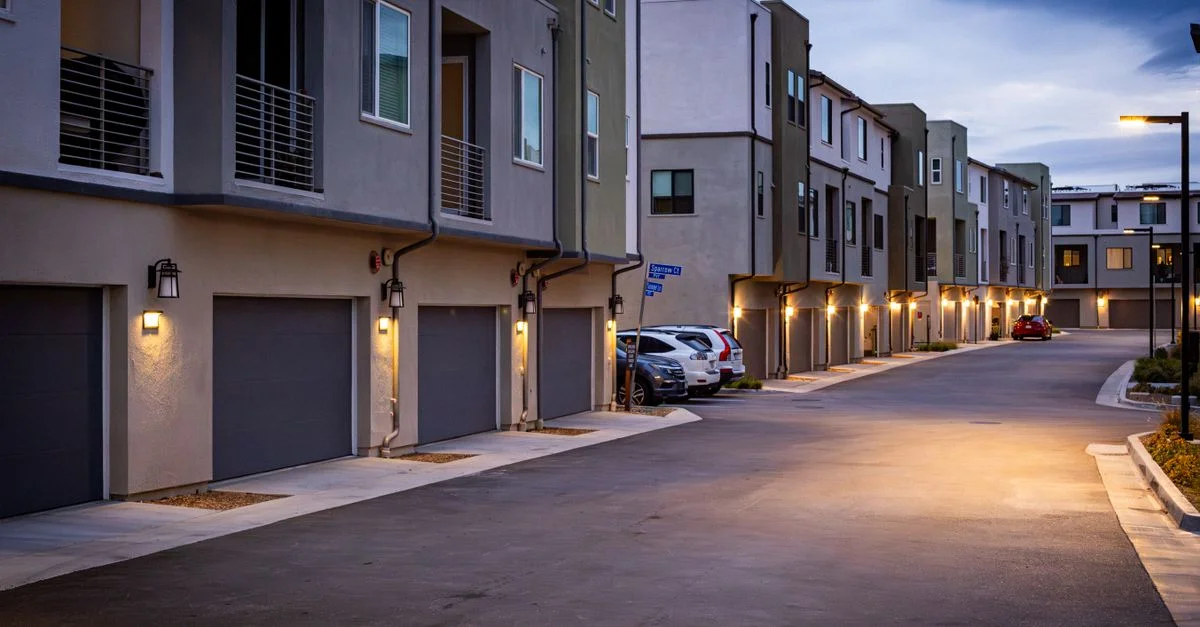 Rue résidentielle calme avec des maisons illuminées au crépuscule, montrant un style architectural moderne.