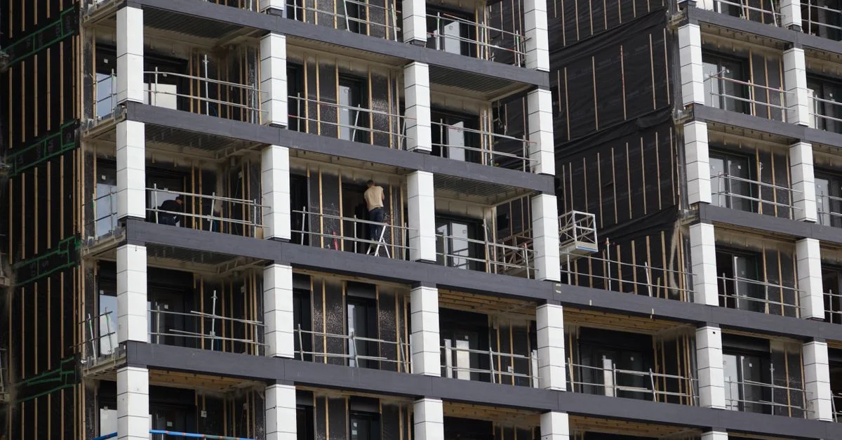 Vue d'un immeuble moderne en construction, avec échafaudages et ouvriers.