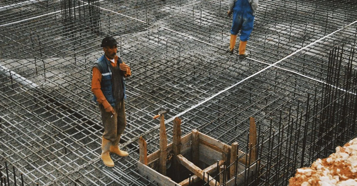 Des ouvriers préparent des armatures en acier sur un chantier de construction pour des fondations en béton.