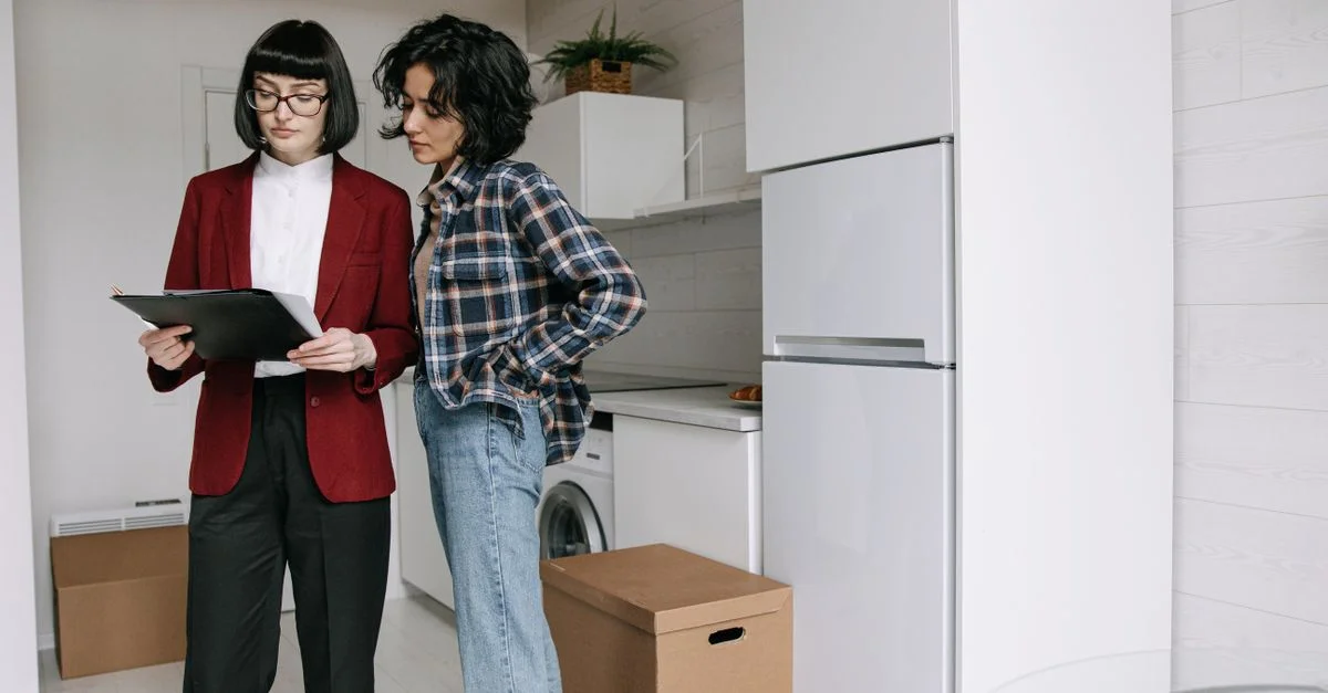 Deux femmes examinant des documents dans une cuisine parmi des cartons de déménagement.