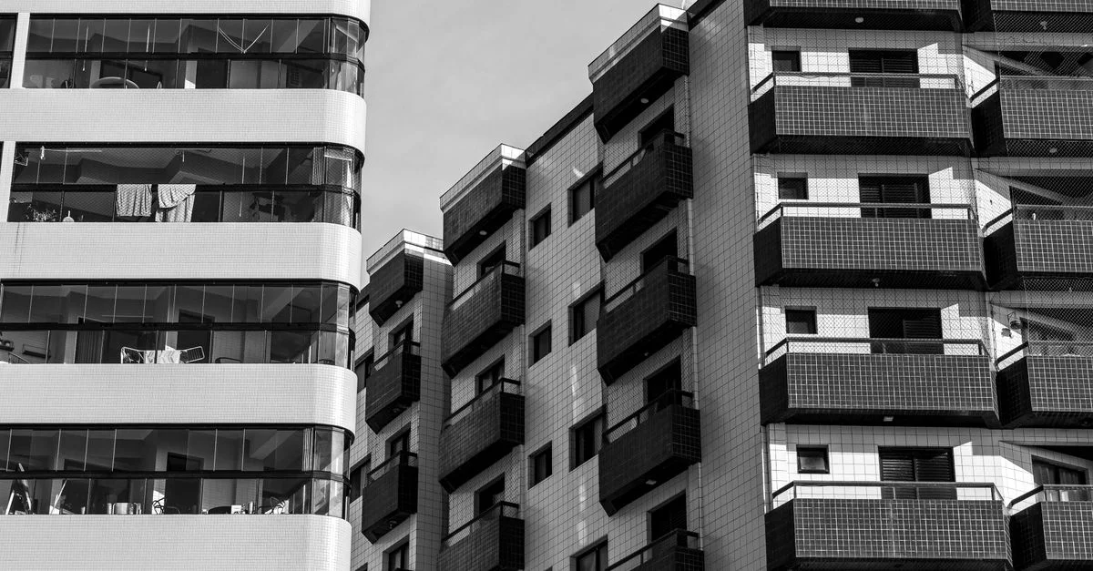 Photo monochrome d'immeubles résidentiels de grande hauteur présentant une architecture moderne et des balcons.